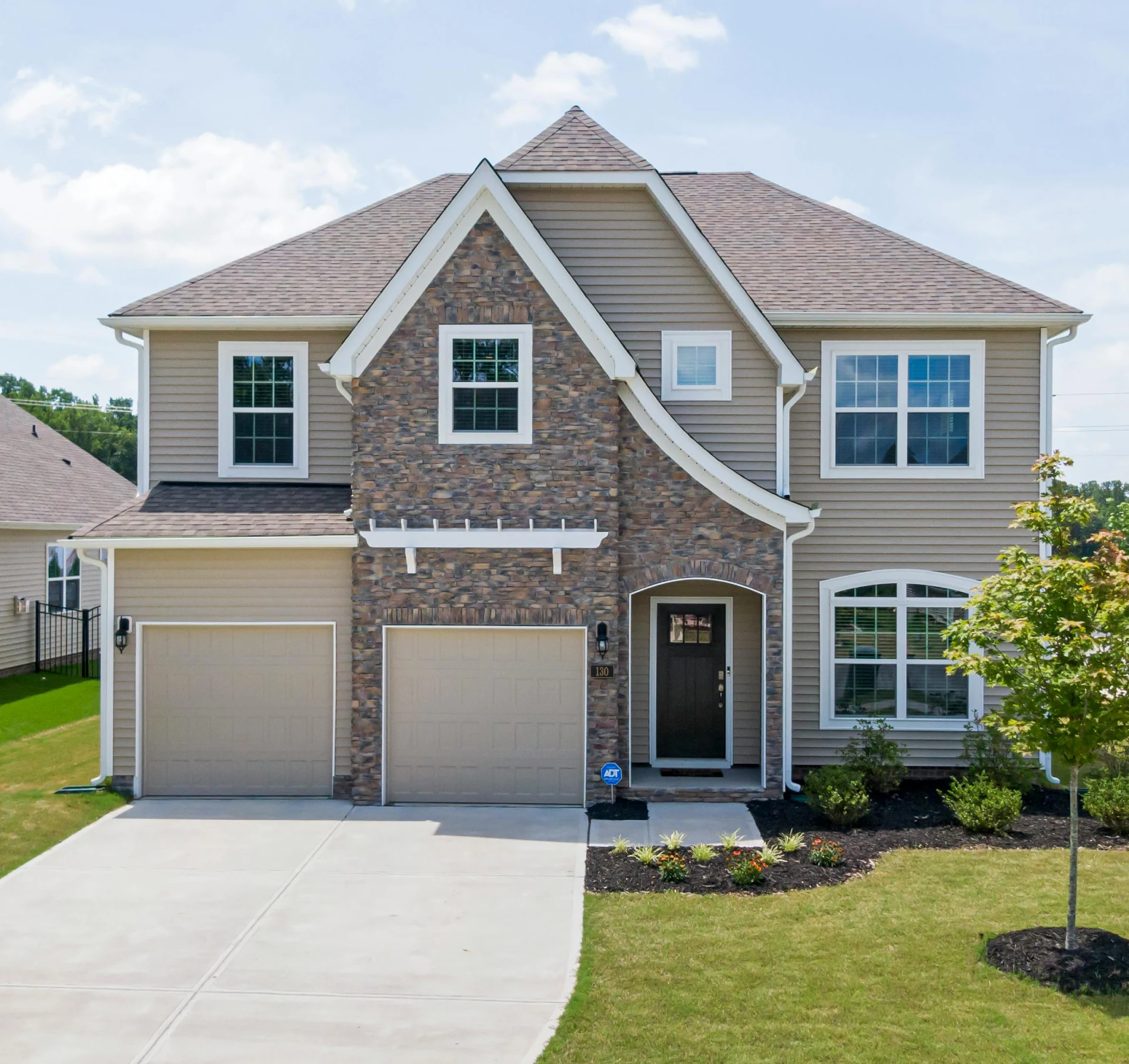 A large house with two garage doors and a driveway.